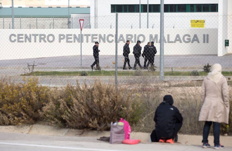 Un grupo de agentes de la Policía Nacional pasean por los alrededores del centro penitenciario Málaga II en Archidona (Málaga), mientras familiares de los inmigrantes argelinos llegados a las costas españolas y que continúan internados en este centro espe