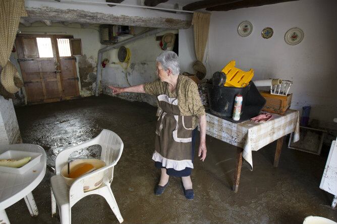 Una vecina del pueblo turolense de La Hoz de la Vieja muestra los daños que causó la fuerte tormenta que provocó el desbordamiento del río Seco y del río Martín