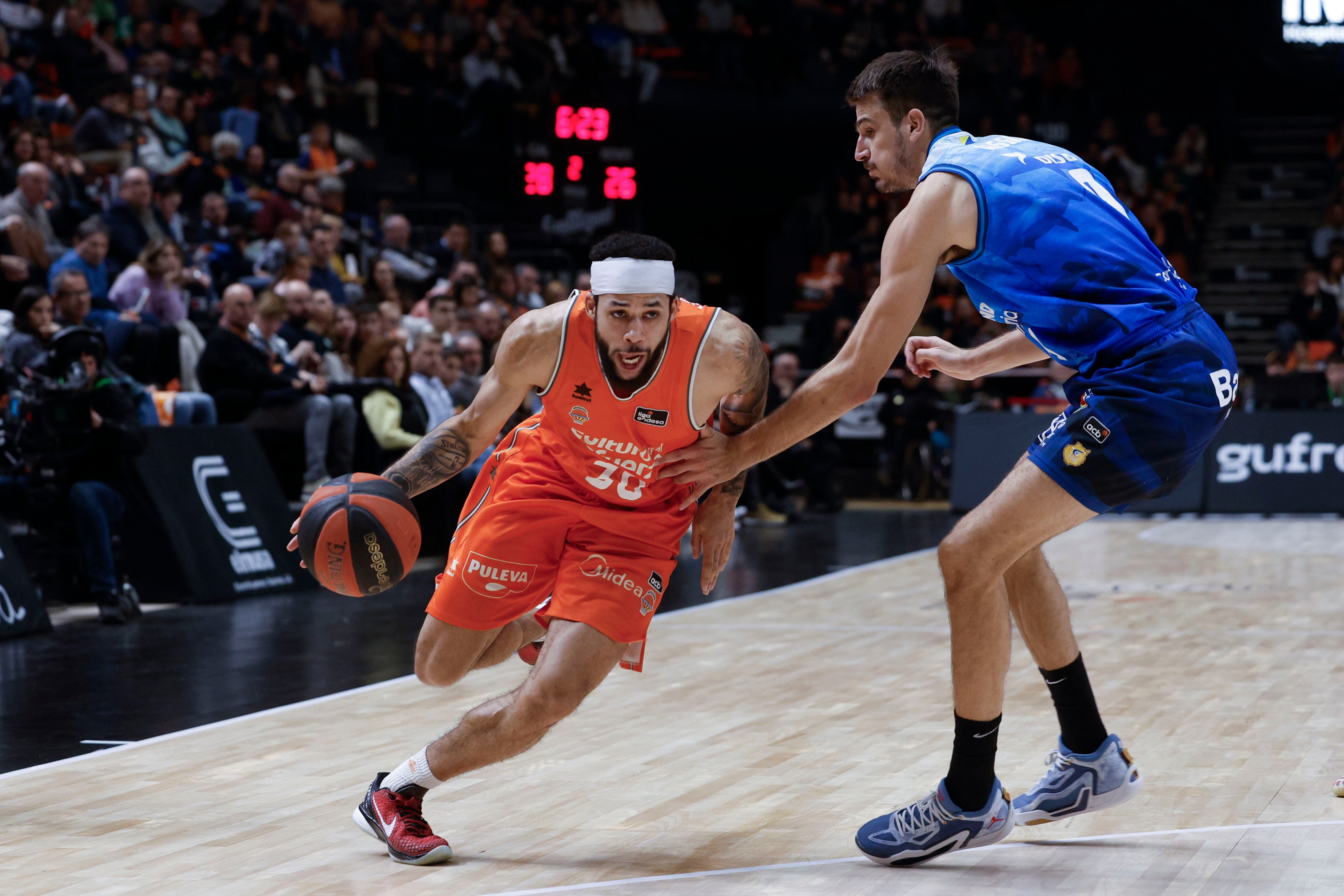 El base canadiense del Valencia Kassius Robertson (i) bota el balón ante el escolta argentino del Gran Canaria Nicolas Brussino (d) durante el partido de la Liga Endesa entre el Valencia Basket y el Gran Canaria celebrado este domingo en el Pabellón Fuente de San Luis de Valencia. EFE/ Kai Försterling