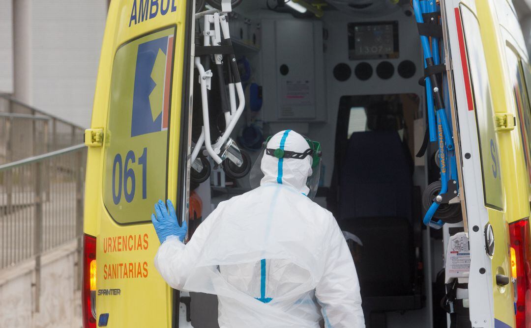 Un trabajador sanitario totalmente protegido cierra la puerta de una ambulancia