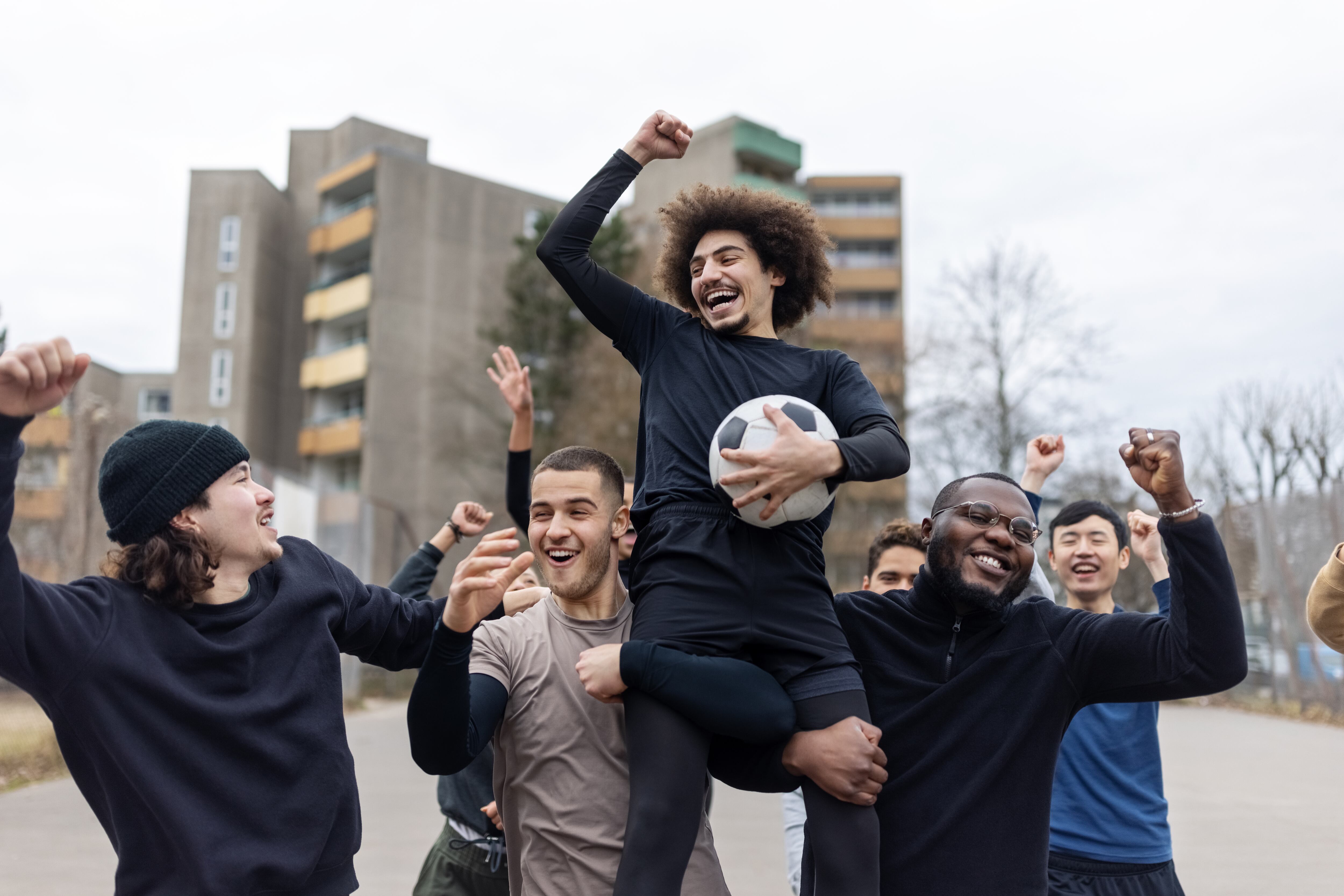 Un grupo de amigos chicos celebra su victoria tras un partido de fútbol