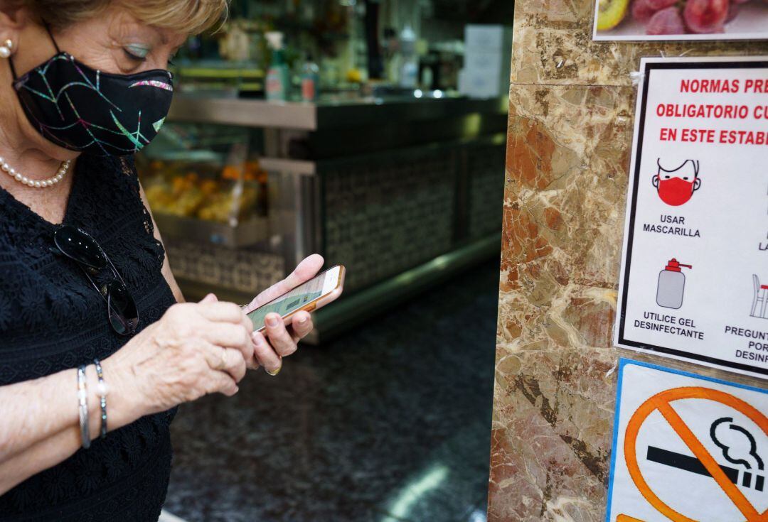 Una mujer busca en su móvil su certificado COVID momentos antes de acceder al interior de una cafetería de Santa Cruz de Tenerife. 