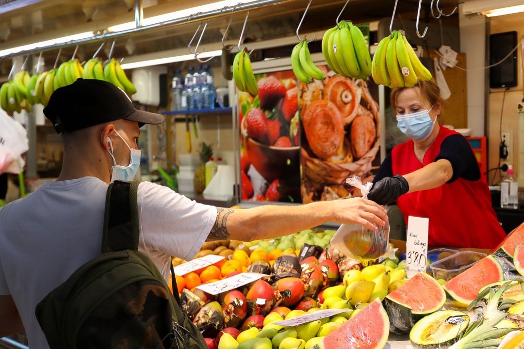 Una trabajadora de una frutería del Mercado Central de Valencia atiende a un cliente