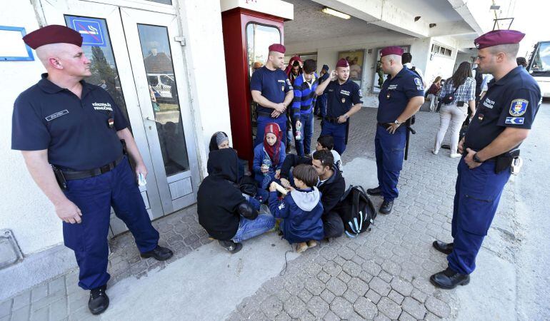 Policías observan a un grupo de refugiados durante el reparto de alimentos en la estación ferroviaria de Bicske (Hungría).