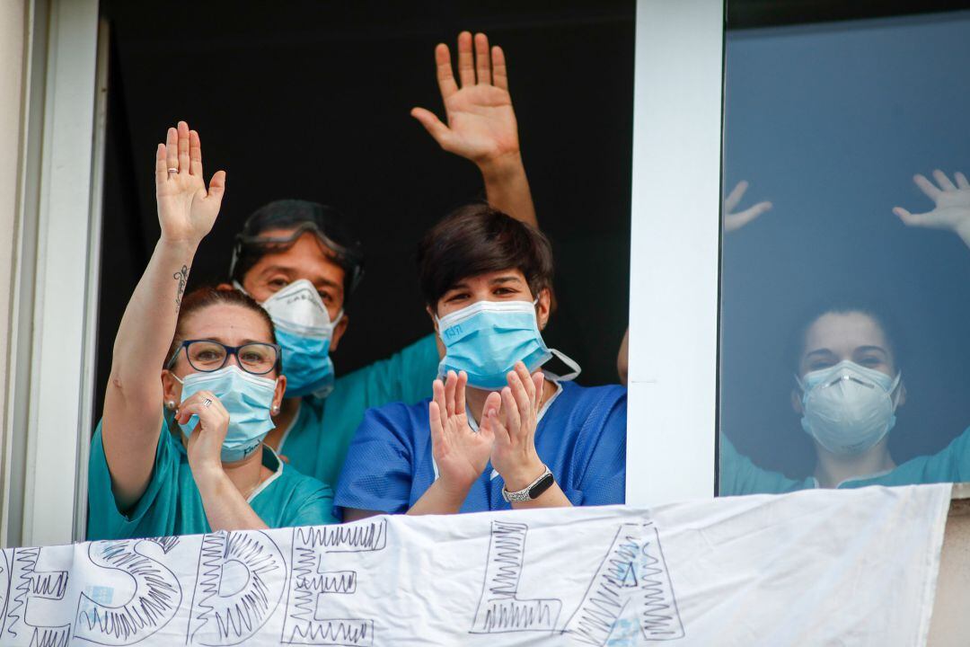 Varios sanitarios aplauden a Fuerzas y Cuerpos de Seguridad desde una ventana durante el homenaje diario a los sanitarios en el Hospital Infanta Elena de Valdemoro