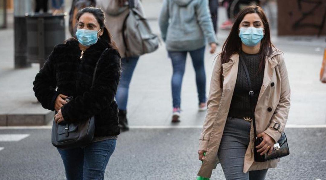 Dos mujeres con mascarilla por la calle.