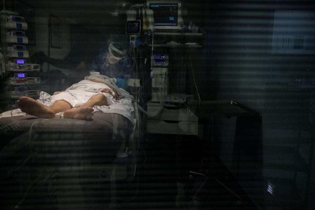 Personal sanitario atendiendo a un paciente de COVID-19 en la UCI. 