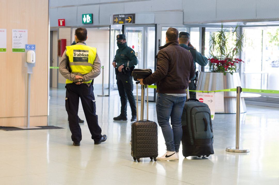 Agentes de la Guardia Civil y empleados de seguridad vigilan a los pasajeros en el interior del Aeropuerto de Ibiza.