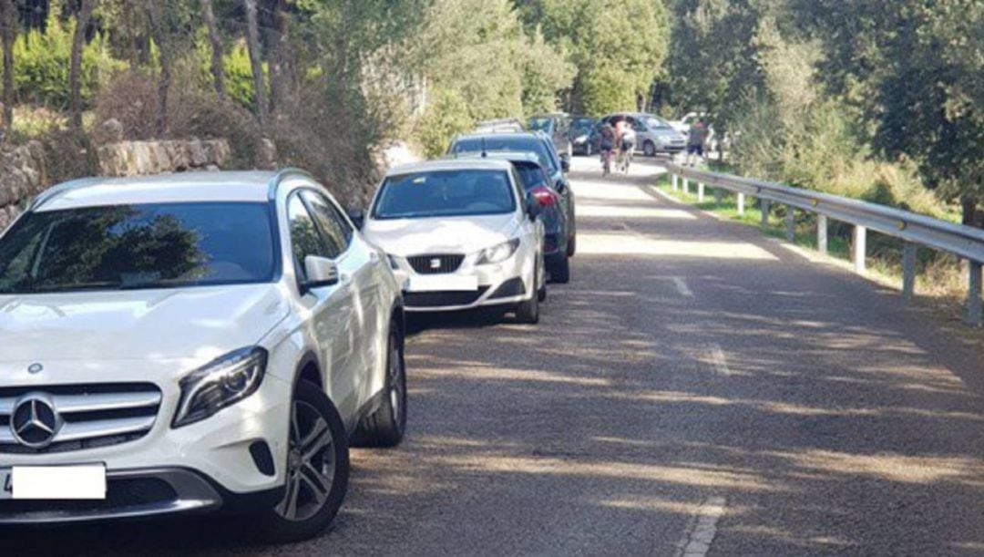 Coches estacionados, ocupando uno de los carriles en una carretera de la Serra