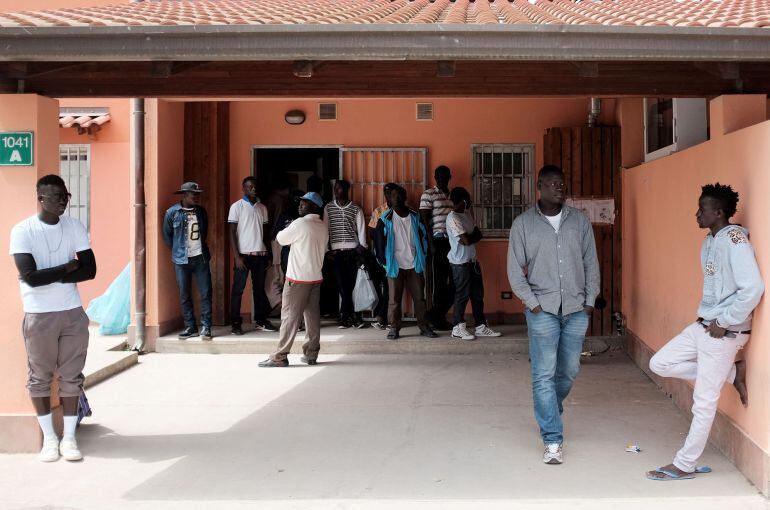 Migrants stand at the Cara Mineo, a hosting centre for asylum seekers, where about 3,200 migrants from North Africa, Ivory Coast, Pakistan, Syria, Afghanistan and other countries are staying in Mineo in the the province of Catania in Sicily on April 21, 2