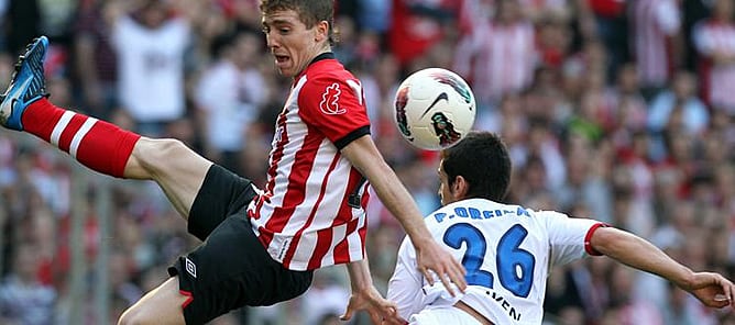 El delantero del Athletic de Bilbao Iker Muniain pugna por un balón con el defensa del Sporting de Gijón Pedro Orfila durante el partido correspondiente a la trigésima jornada de Liga de Primera División disputado entre ambos equipos