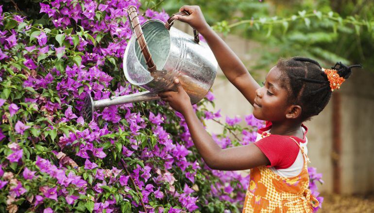 Una niña regando las flores.