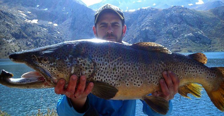 Un pescador mosta la truita que va pescar a Estany Gento, a la Vall Fosca