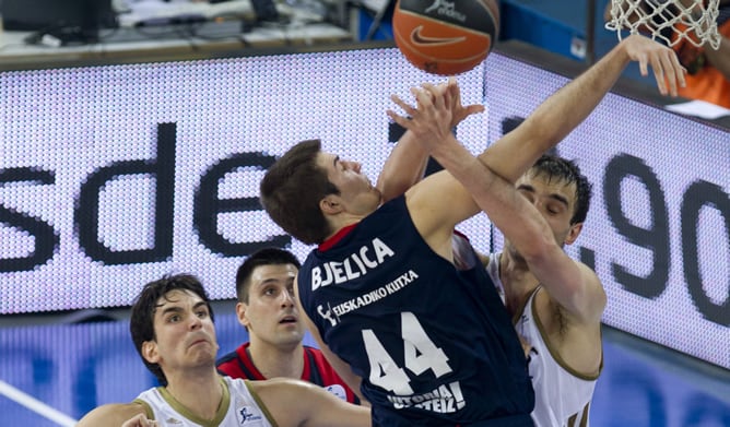 El pívot bosnio del Real Madrid, Mirza Begic (d), y el alero serbio del Caja Laboral Baskonia de Vitoria, Nemanja Bjelica, se disputan un rebote ante el alero madridista Carlos Suárez (i), y el ala-pívot serbio del equipo vasco Milko Bjelica, durante el t