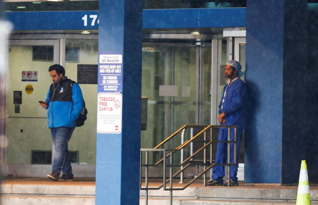 Un sanitario del Hospital Universitario de Illinois descansa en la entrada del edificio tras conocerse 12 casos positivos por coronavirus entre el personal de enfermería.