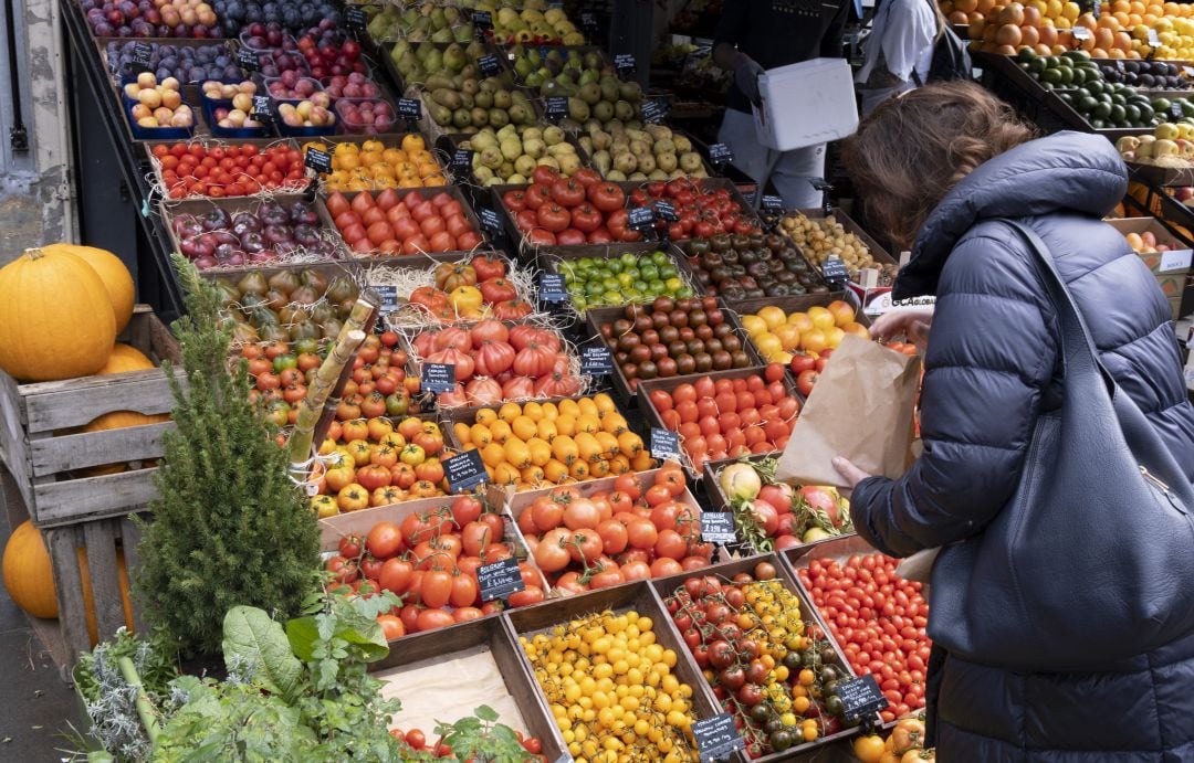 Una mujer adquiere varios productos en la frutería.