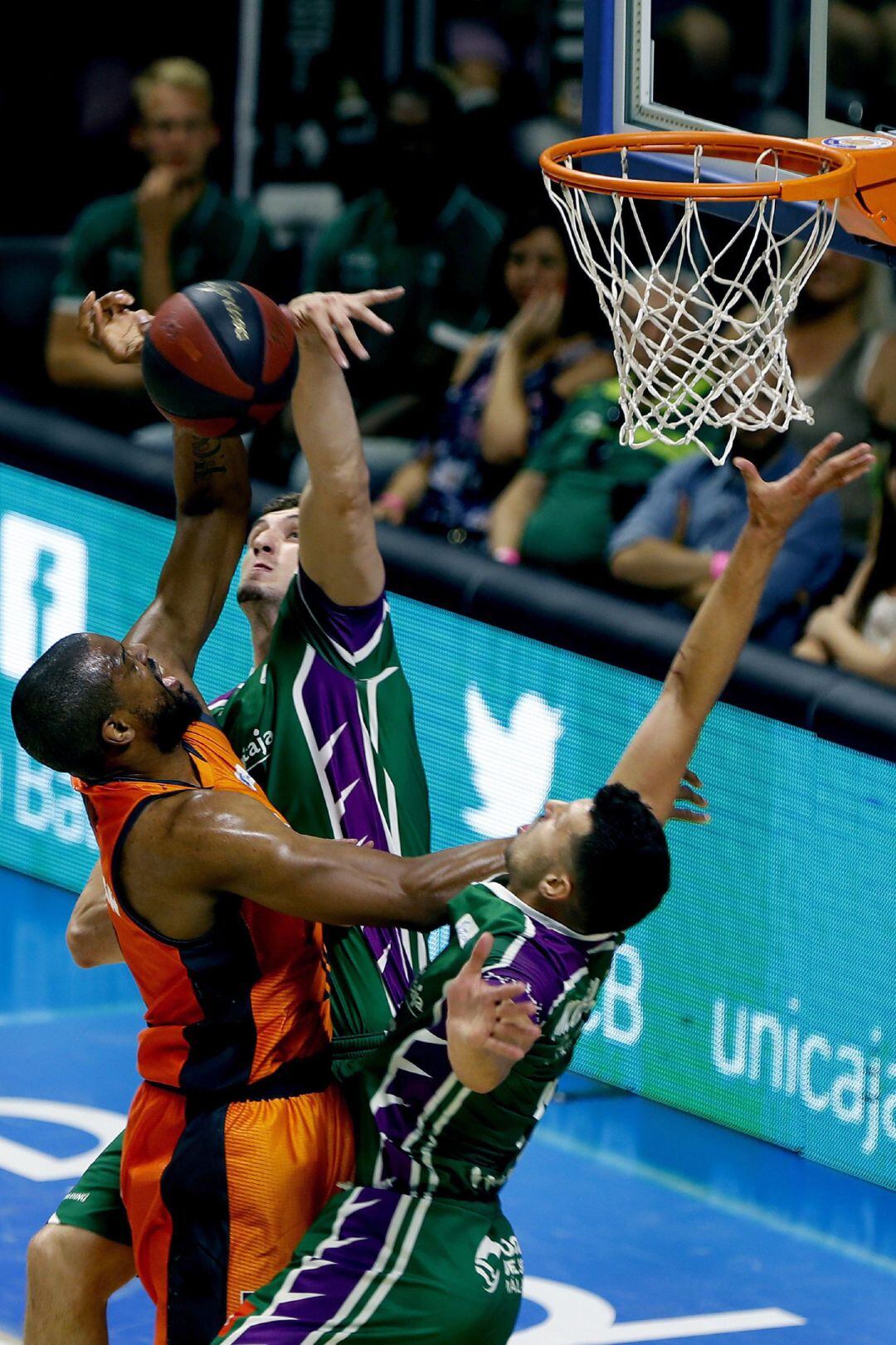 GRAF2550. MÁLAGA, El ala-pívot estadounidense del Valencia Basquet Will Thomas (i) recibe un tapón del pívot del Unicaja Rubén Guerrero (c) al intento de bloqueo del alero serbio del Unicaja Dragan Milosavljevic (d), durante el segundo partido del playoff de cuartos de final de la Liga Endesa que se disputa esta tarde en el Palacio de Deportes José Mª Martín Carpena, en Málaga. EFE, Jorge Zapata