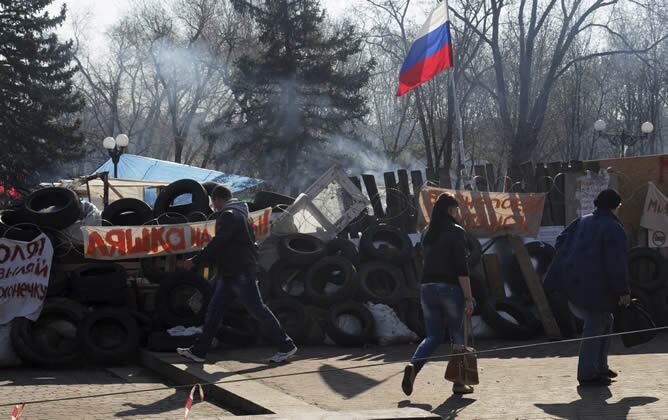 Ucranianos pasan delante de una barricada junto a un edificio ocupado por activistas prorrusos en Lugansk