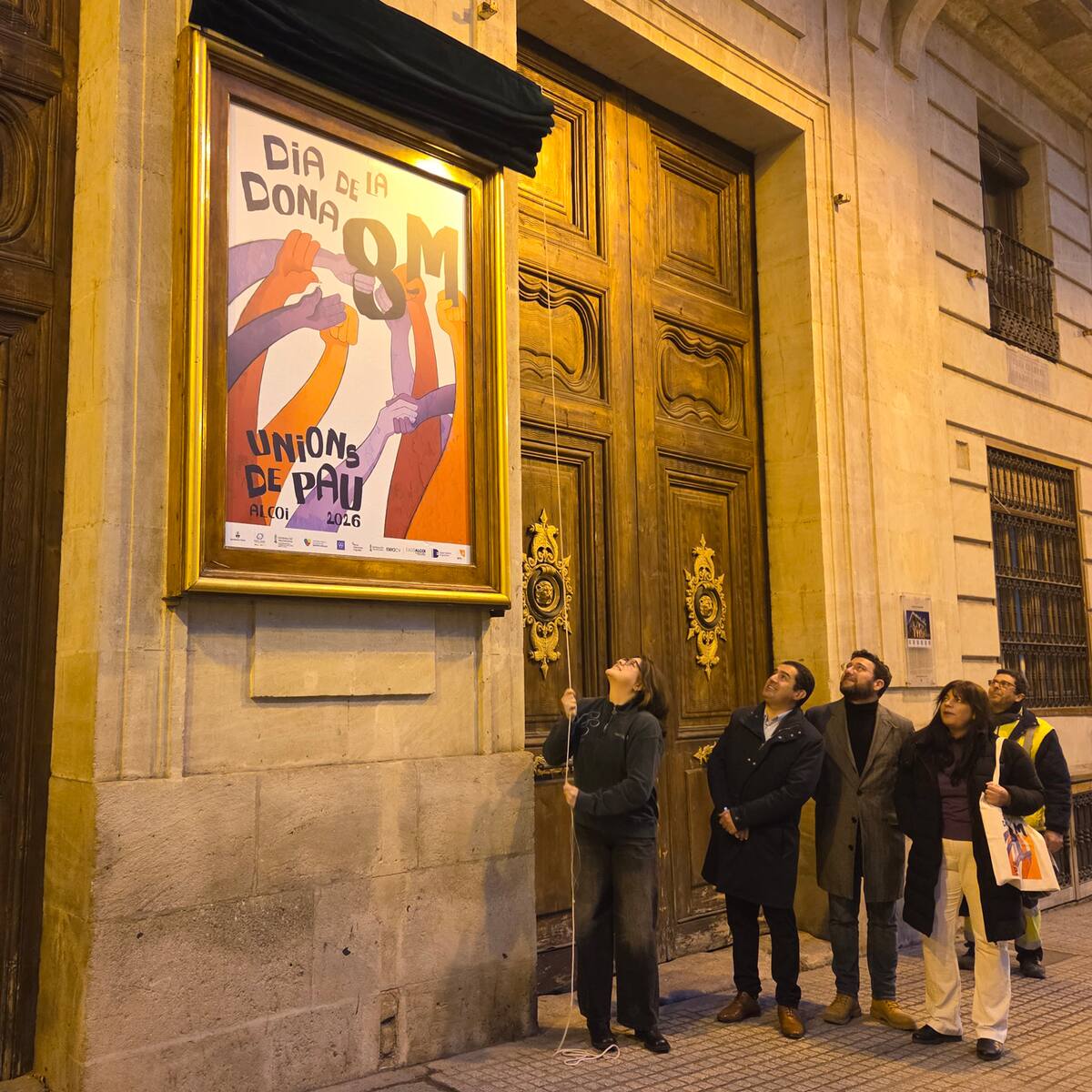 Los actos con motivo del 8 de marzo se inician con el descubrimiento del cartel en la fachada del Ayuntamiento