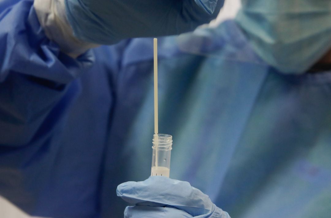 Una trabajadora sanitaria sostiene una probeta con una prueba PCR