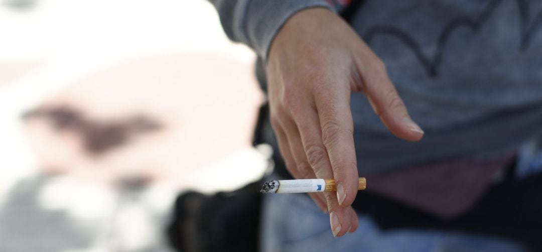 Persona fumando un cigarro en la calle