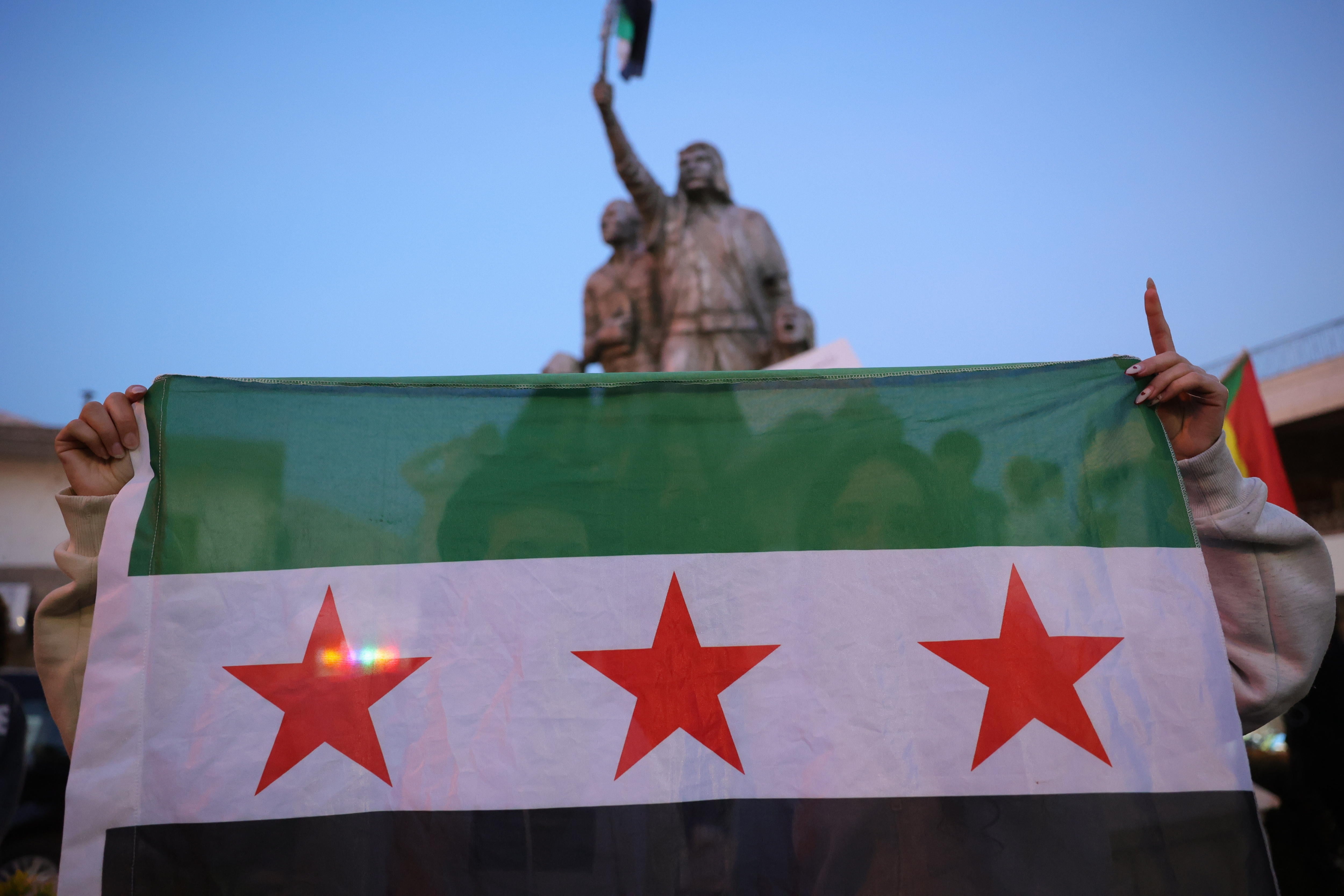 Imagen de dos mujeres con la nueva bandera de Siria durante unas protestas en Damasco