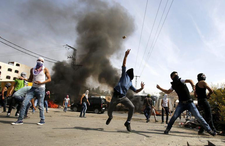 Varios palestinos lanzan piedras durante su enfrentamiento con la policía palestina. 