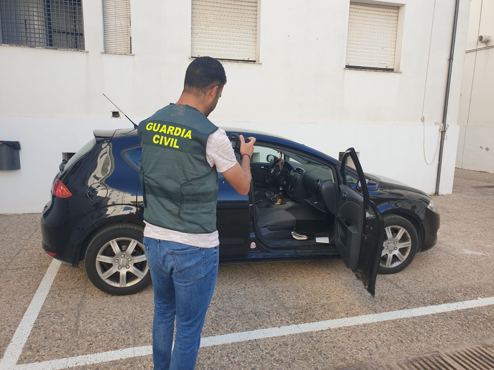 Un guardia civil investiga uno de los vehículos en los que se produjo un robo.