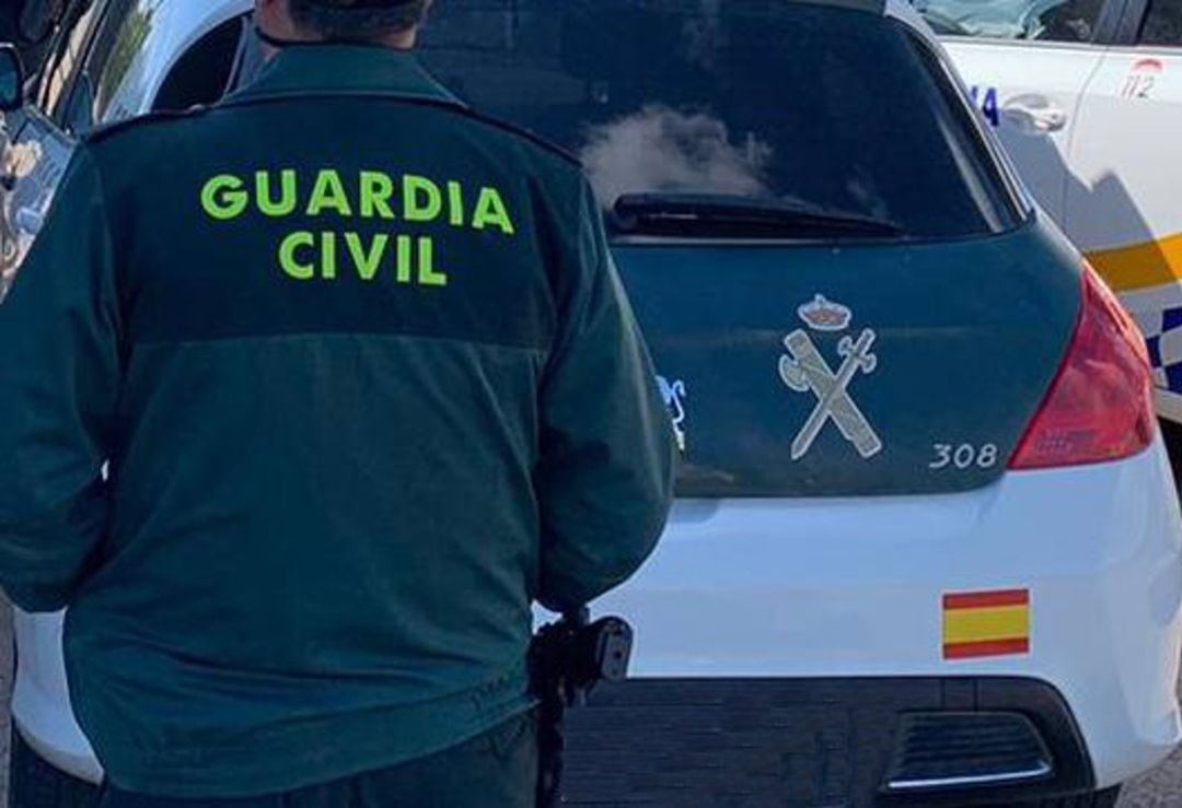 Imagen de Archivo de un agente de la Guardia Civil de espaldas y junto a un vehículo oficial del cuerpo