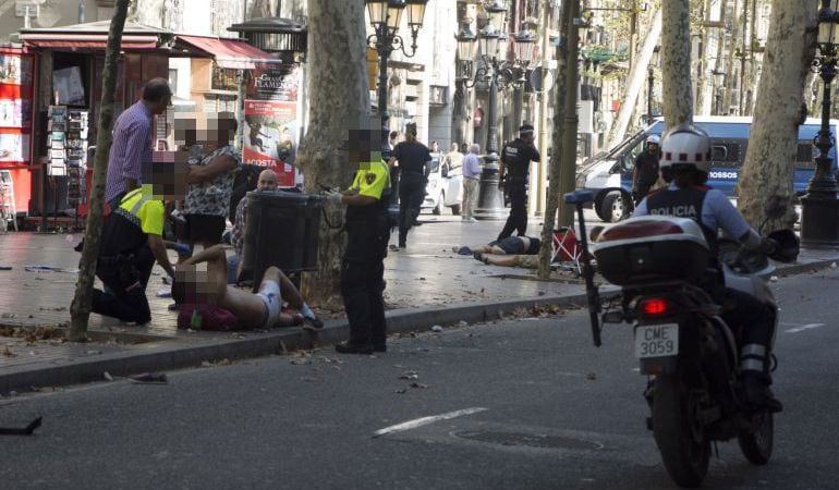 Efectivos policiales atienden a una de las víctimas de un atropello masivo de una furgoneta que ha arrollado a varias personas que paseaban por las Ramblas de Barcelona.