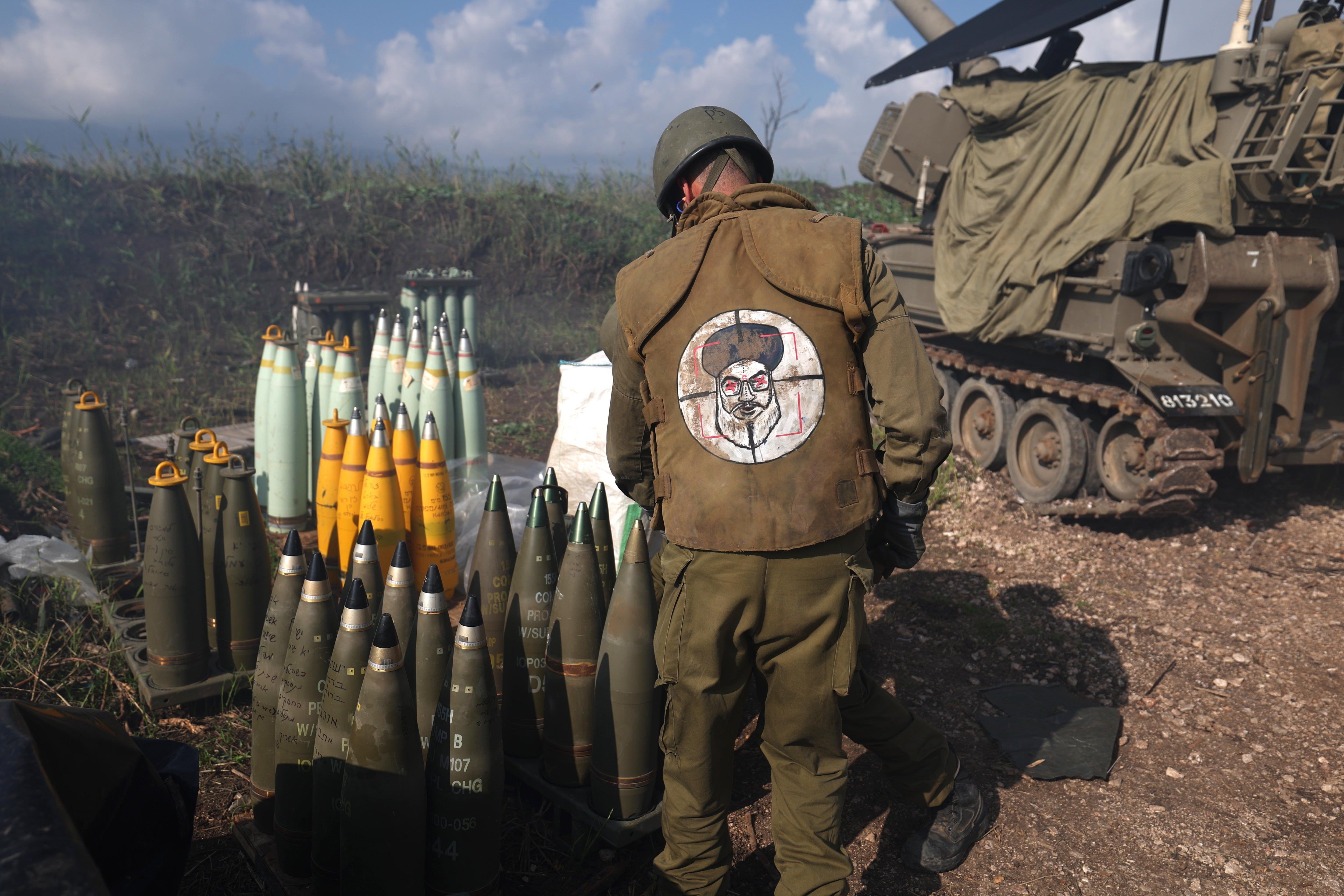 Un soldado israelí rodeado de misiles en la frontera con el Líbano y portando un chaleco con la cara, a modo de diana, del líder de Hezbolá, Hassan Nasrallah