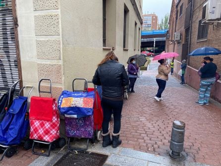 Decenas de personas esperan con sus carritos al reparto de comida