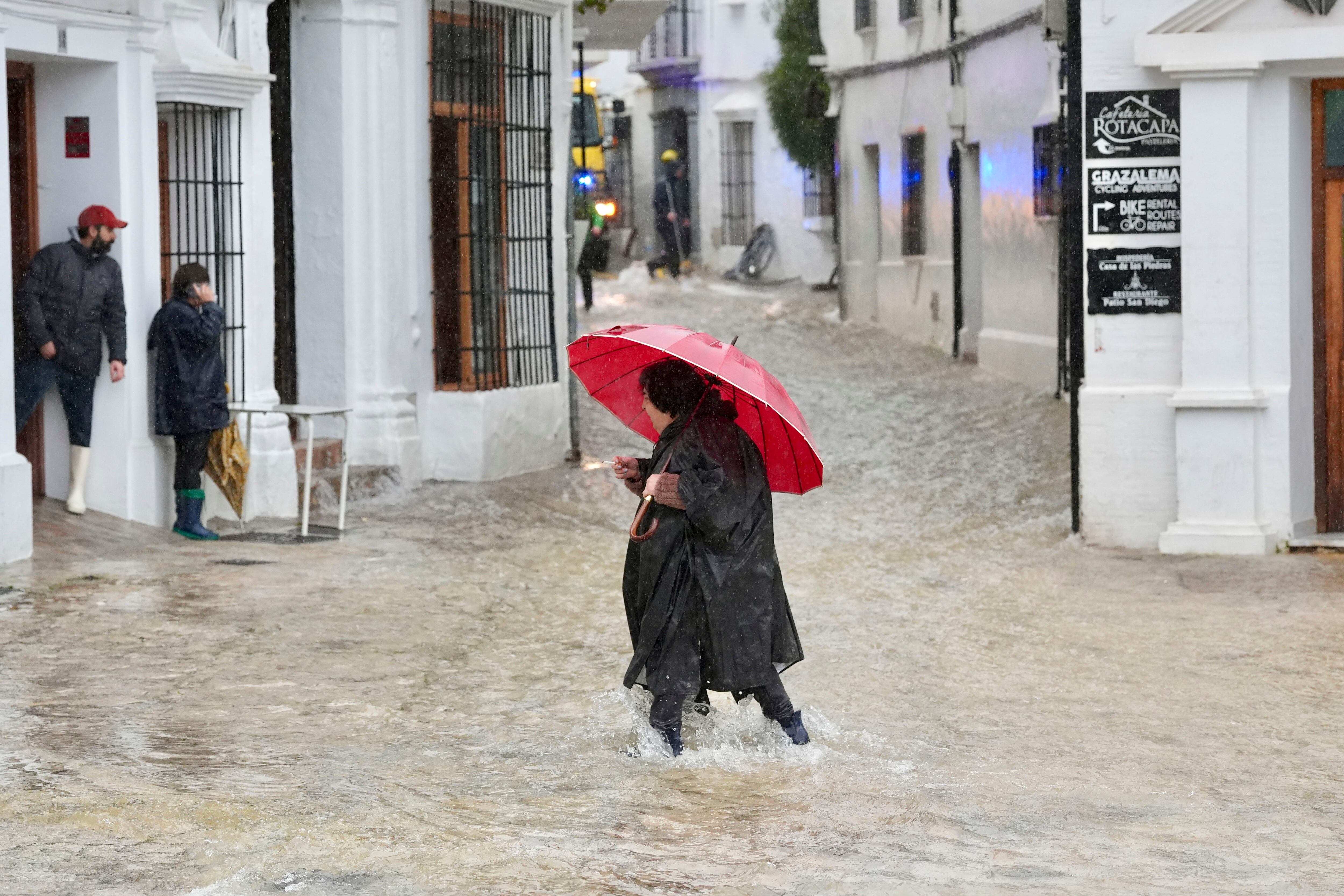 Una vecina de Grazalema (Cádiz) camina por una calle inundada debido a las intensas lluvias que se registran en la localidad gaditana.