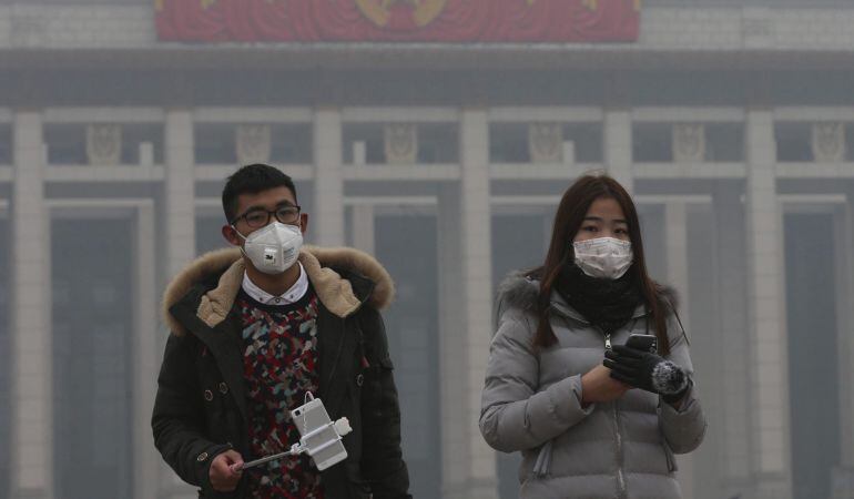 Una pareja usa mascarillas para protegerse de la contaminación ambiental durante una visita a la plaza de Tiananmen en Pekín (China).