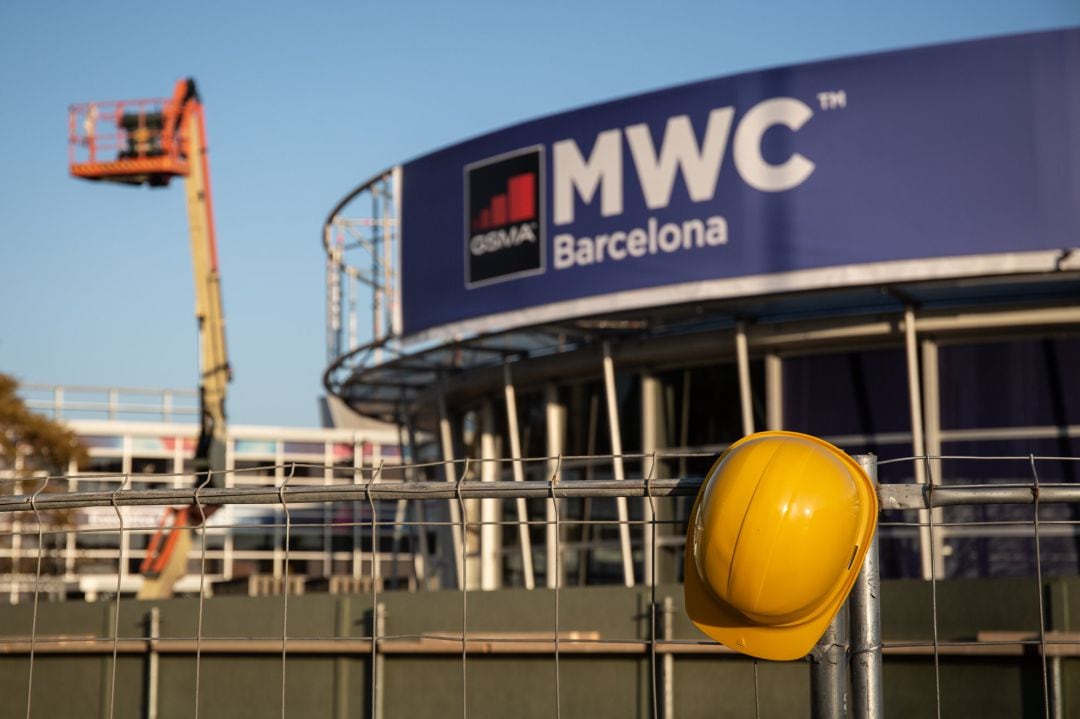 Un casco de obra amarillo colgado en una de las vallas que cierran el recinto del Mobile World Congress durante el desmantelamiento de los stands tras la cancelación de la feria por la crisis del coronavirus y las anulaciones de empresas