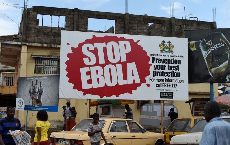 (FILES) This file picture dated November 7, 2014 shows people walking past a billboard reading &quot;Stop Ebola&quot; in Freetown. Sierra Leone said on March 19, 2015 it will confine around 2.5 million people to their homes across the capital and in the north in a 