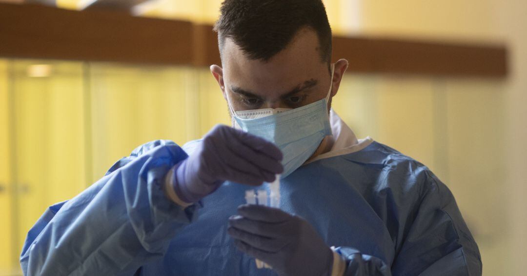 Un trabajador sanitario sostiene una probeta en un dispositivo de cribado masivo de antígenos.