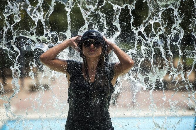 Una joven toma un baño en una fuente de Córdoba ante el calor sofocante.