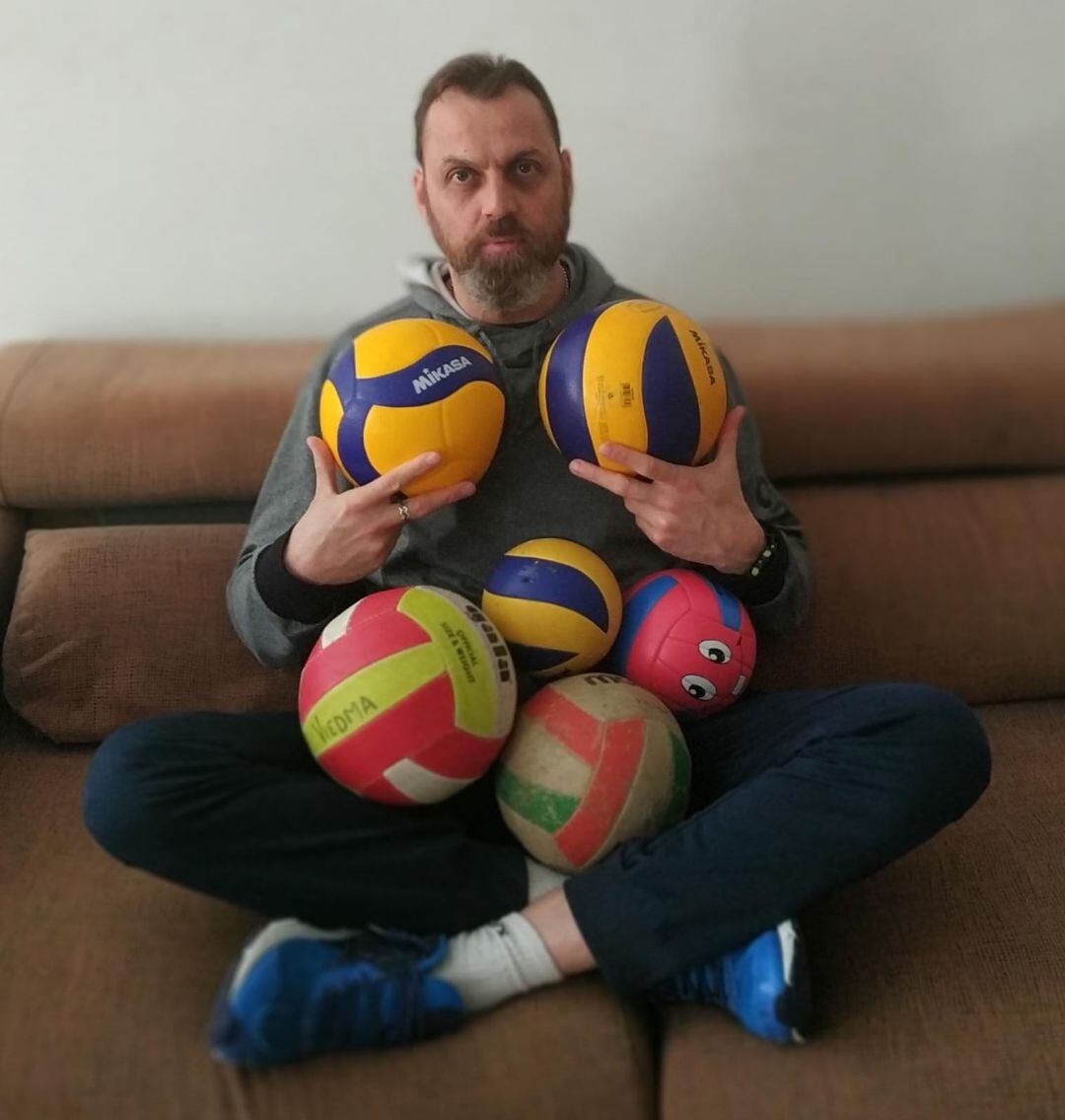 Charly Carreño rodeado de balones de voleibol.