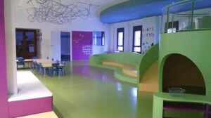 Imatge de l'aula d'infantil, on s'ha instal·lat un tobogan, unes grades i una zona de taules per a tallers