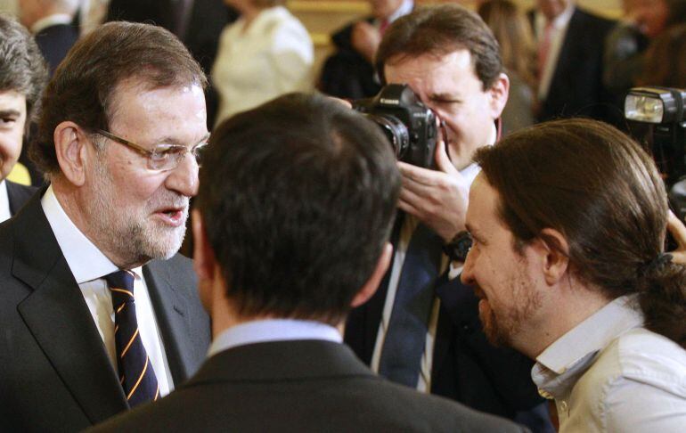 El presidente del Gobierno y candidato a la reelección, Mariano Rajoy (i), conversa con los líderes y candidatos de Podemos, Pablo Iglesias (d), y UPyD, Andrés Herzog, a su llegada a la recepción celebrada en el Congreso de los Diputados con motivo del XX