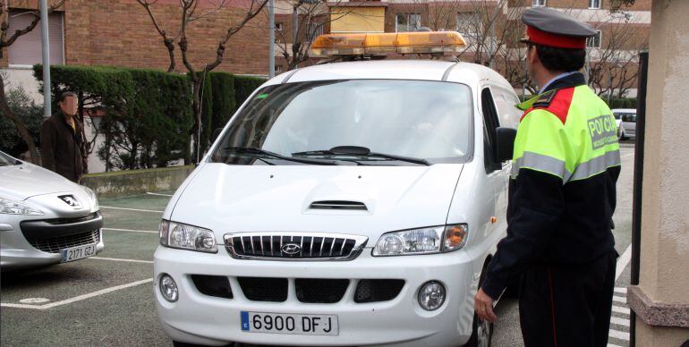 Un agent dels Mossos d'Esquadra al costat del vehicle funerari, sortint de la finca de Tarragona on s'ha produït l'homicidi.
