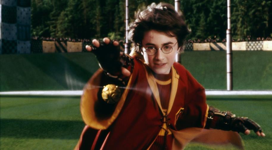 Harry Potter extiende el brazo para atrapar la snitch dorada en una de sus películas