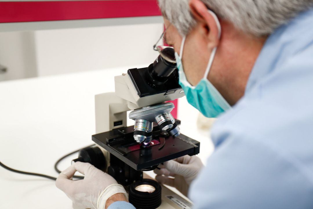 Imagen de archivo de un investigador mirando por un microscopio.