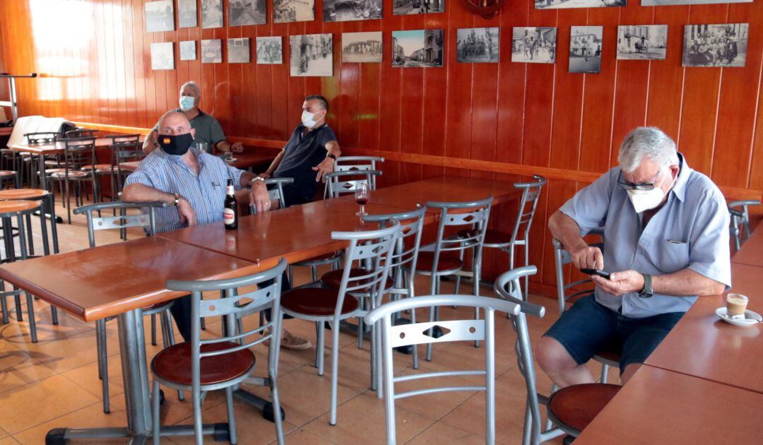 Varios hombres con mascarillas en el interior de un bar.