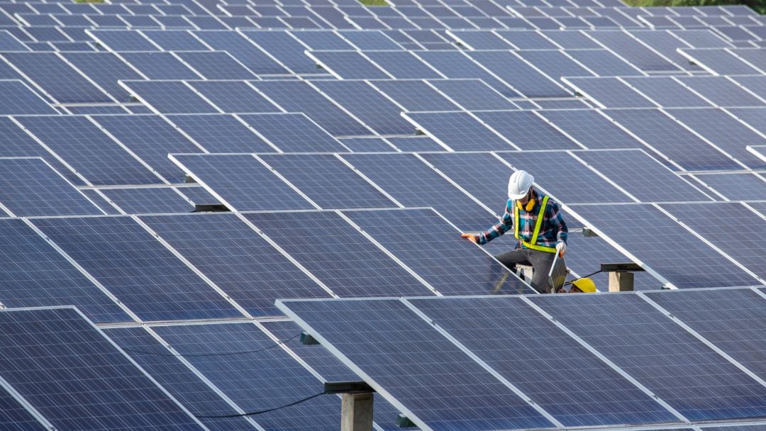 Un operario instala una placa solar en una gran planta fotovoltaica. 