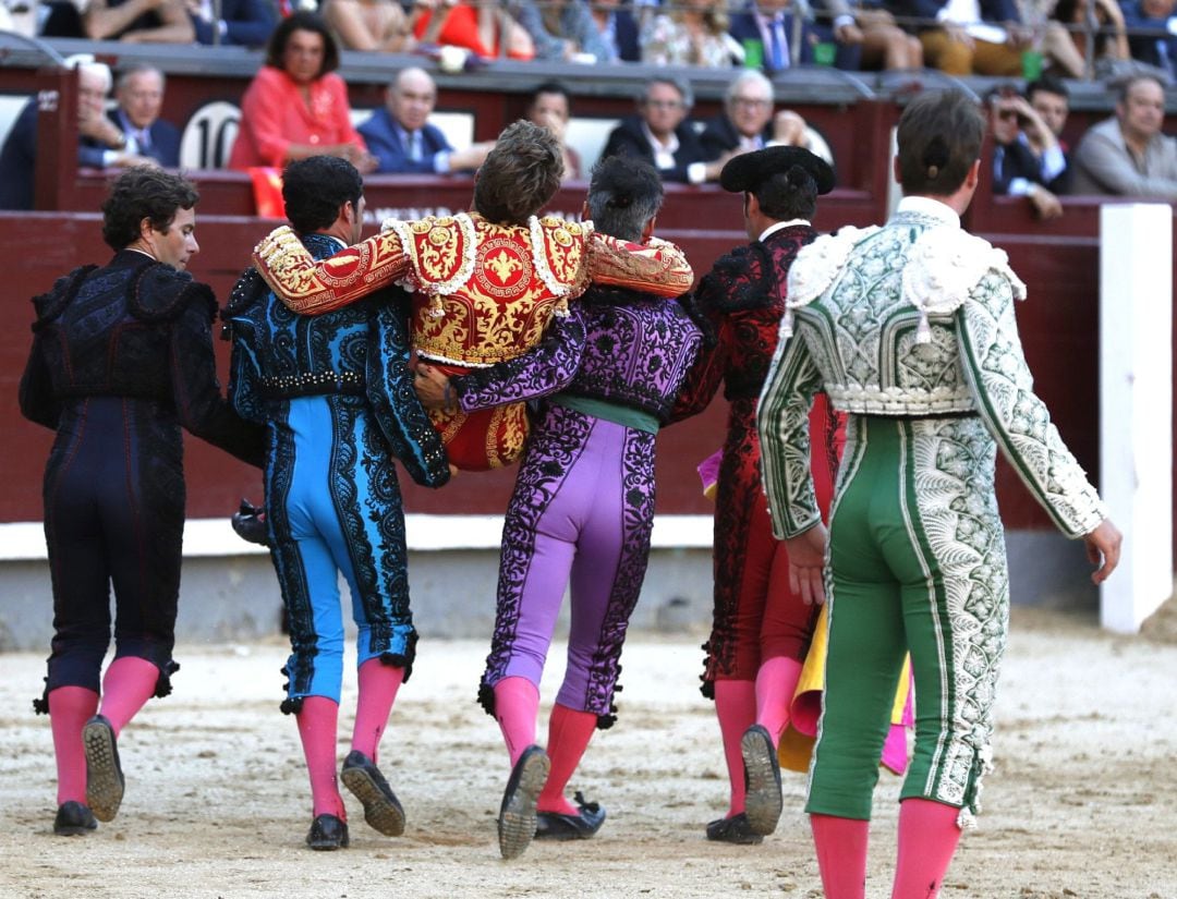 El diestro Manuel Escribano es llevado a la enfermería por su cuadrilla tras sufrir una cogida en su segundo toro durante el decimoséptimo festejo de la Feria de San Isidro, esta tarde en la plaza de toros de Las Ventas, donde comparte cartel con los matadores Román, y el peruano Roca Rey, lidiando reses de la ganadería de Adolfo Martín