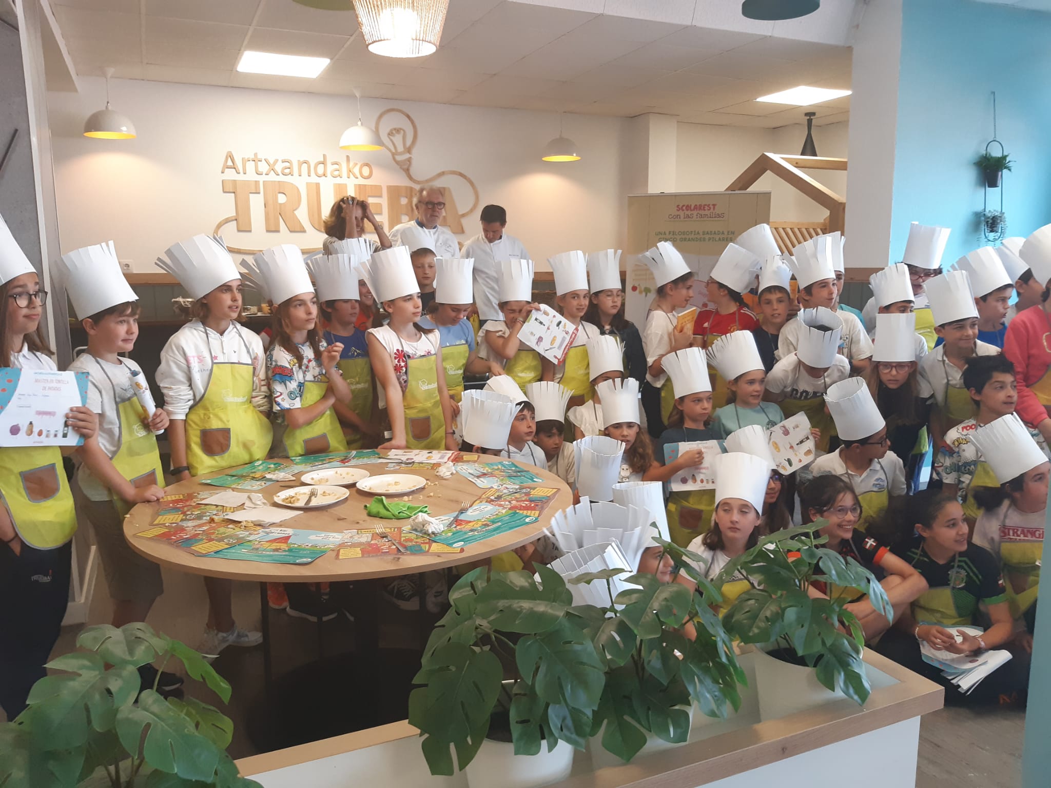 Niños y niñas posan junto a Ramón Roteta en el comedor del Colegio Trueba