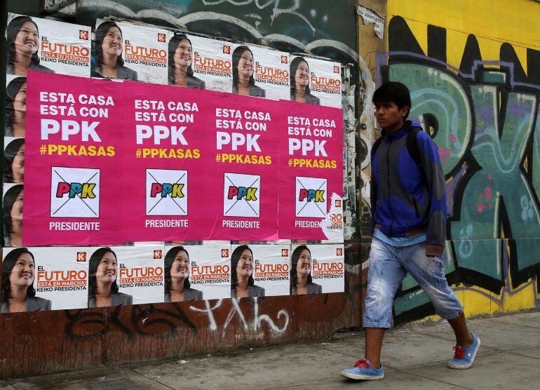 Un hombre camina junto a algunos carteles de los dos candidatos a la segunda vuelta de las Elecciones Generales 2016