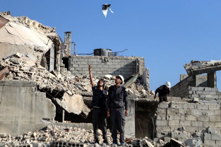 Un hombre libera a una paloma blanca, símbolo de la paz, durante una protesta en Zamalka (Siria) hoy, 22 de agosto del 2017, en memoria del ataque con armas químicas que se produjo en agosto del 2013 en la localidad siria de Ghouta, y en el que murieron m